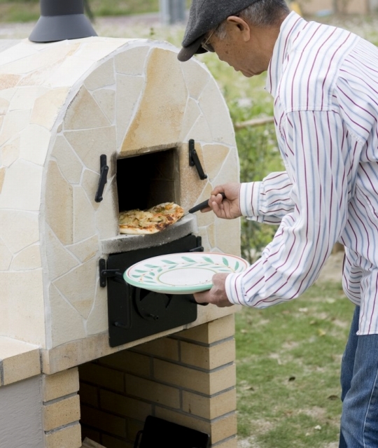 ピザ窯で手作りピザを焼くご主人